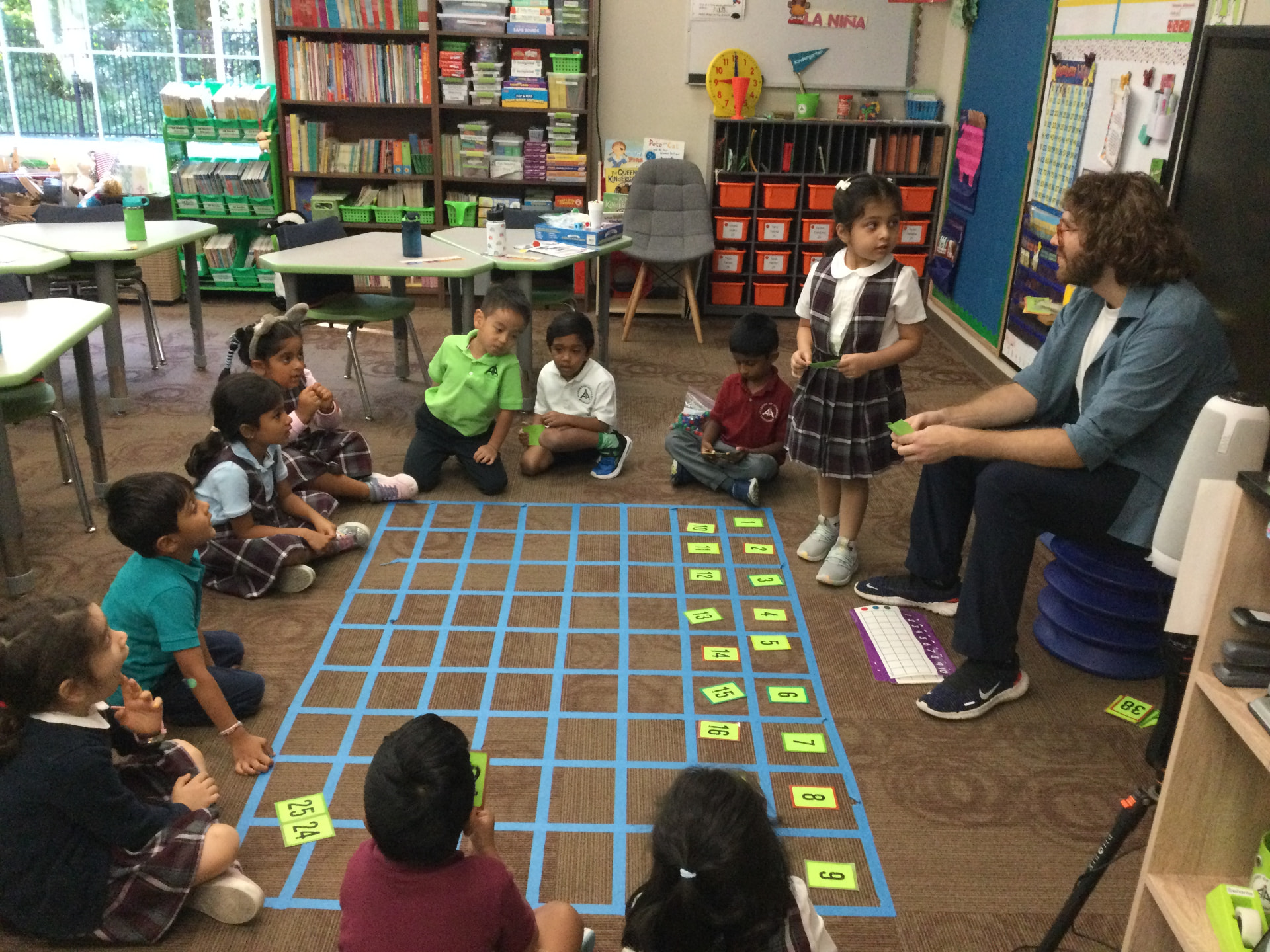 Kindergarten students working through a floor number grid with their teacher