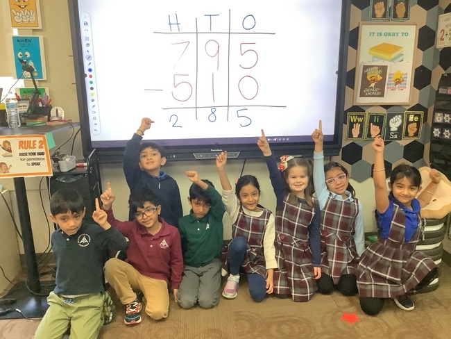 First grade students raising their hands during a math lesson